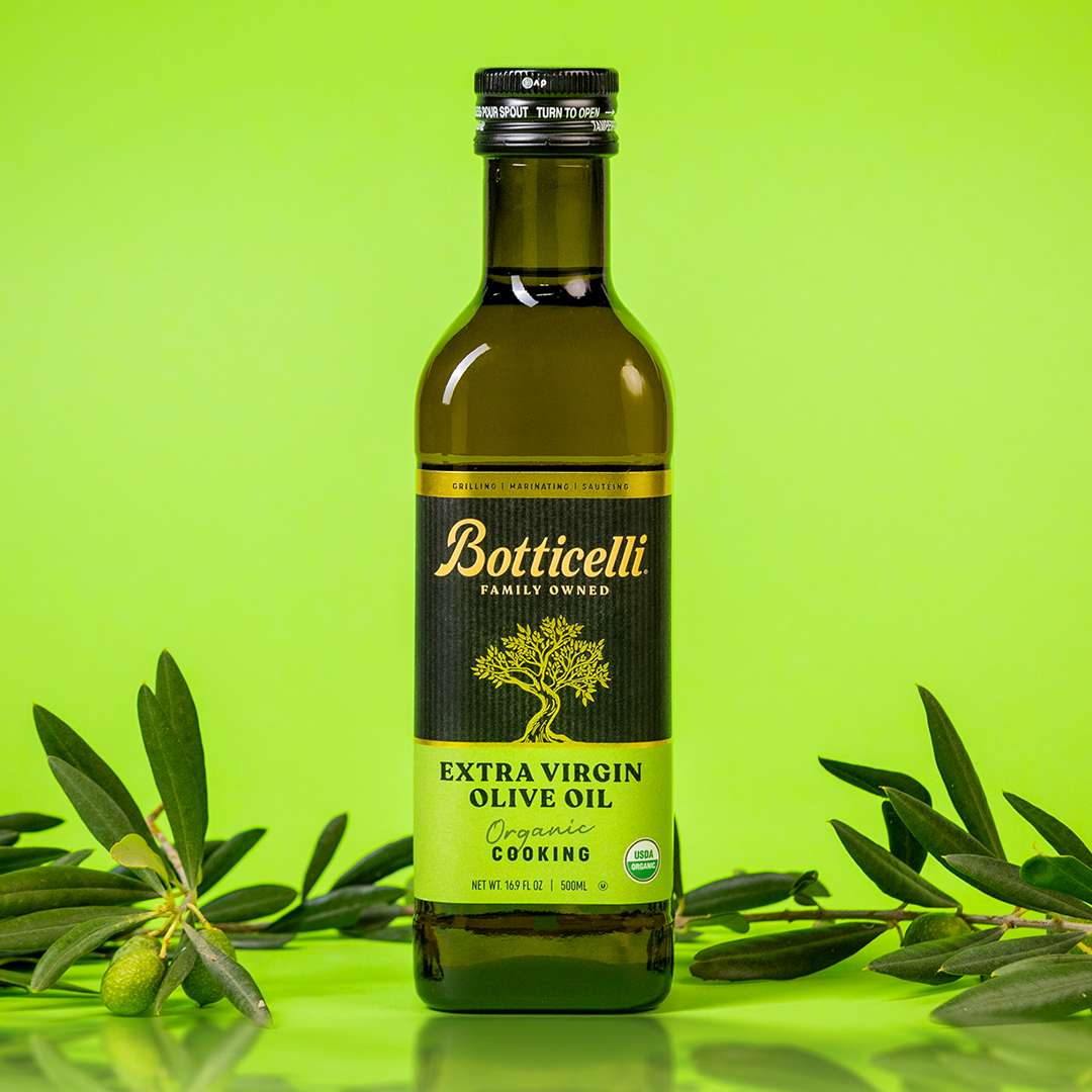 Bottle of Botticelli Organic cooking extra virgin olive oil with olive branches on a green background
