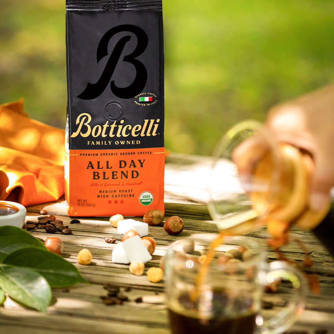 Botticelli All Day Blend coffee packaging with a cup of coffee being poured on a wooden surface.