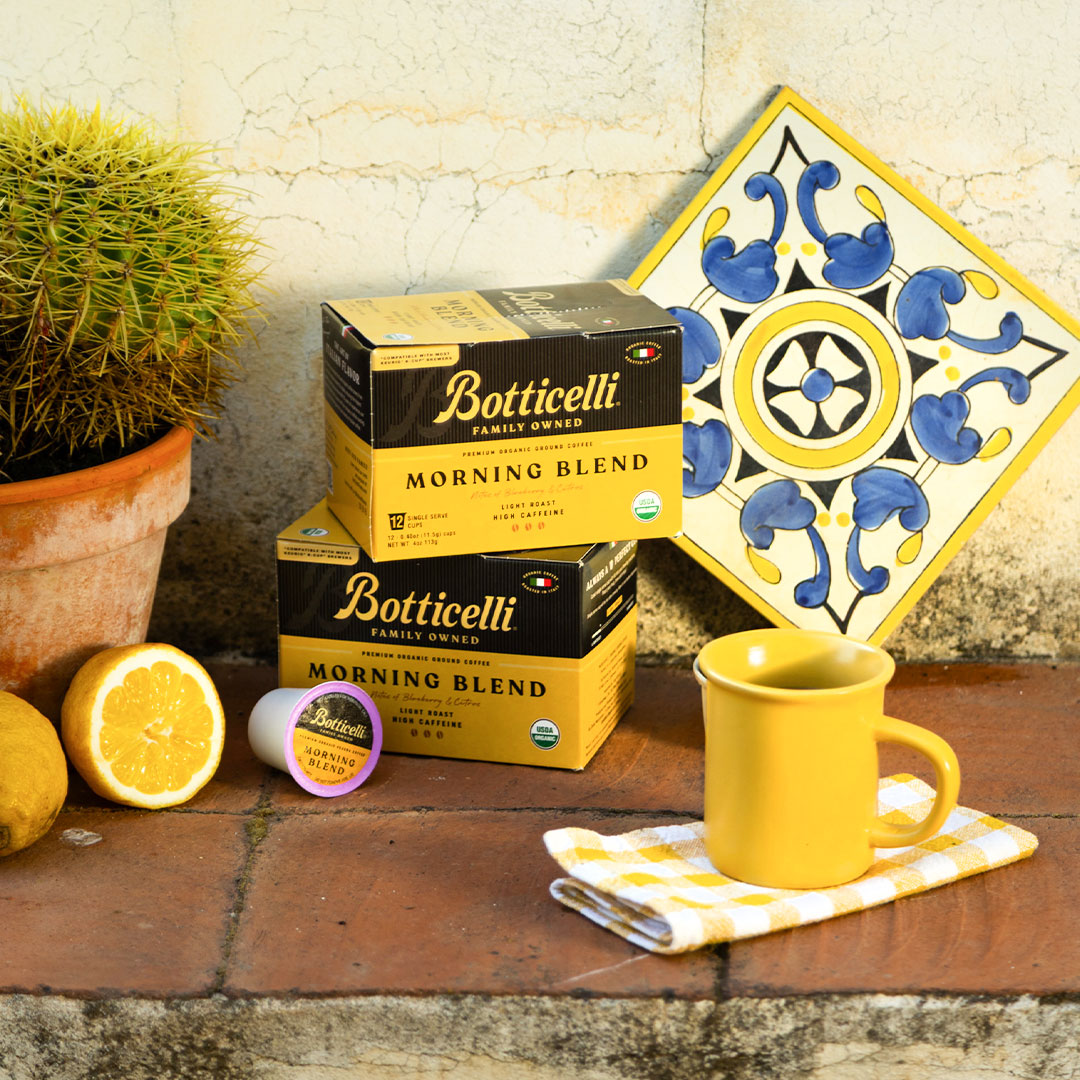 Botticelli coffee boxes with a yellow mug and decorative tile on a rustic surface.