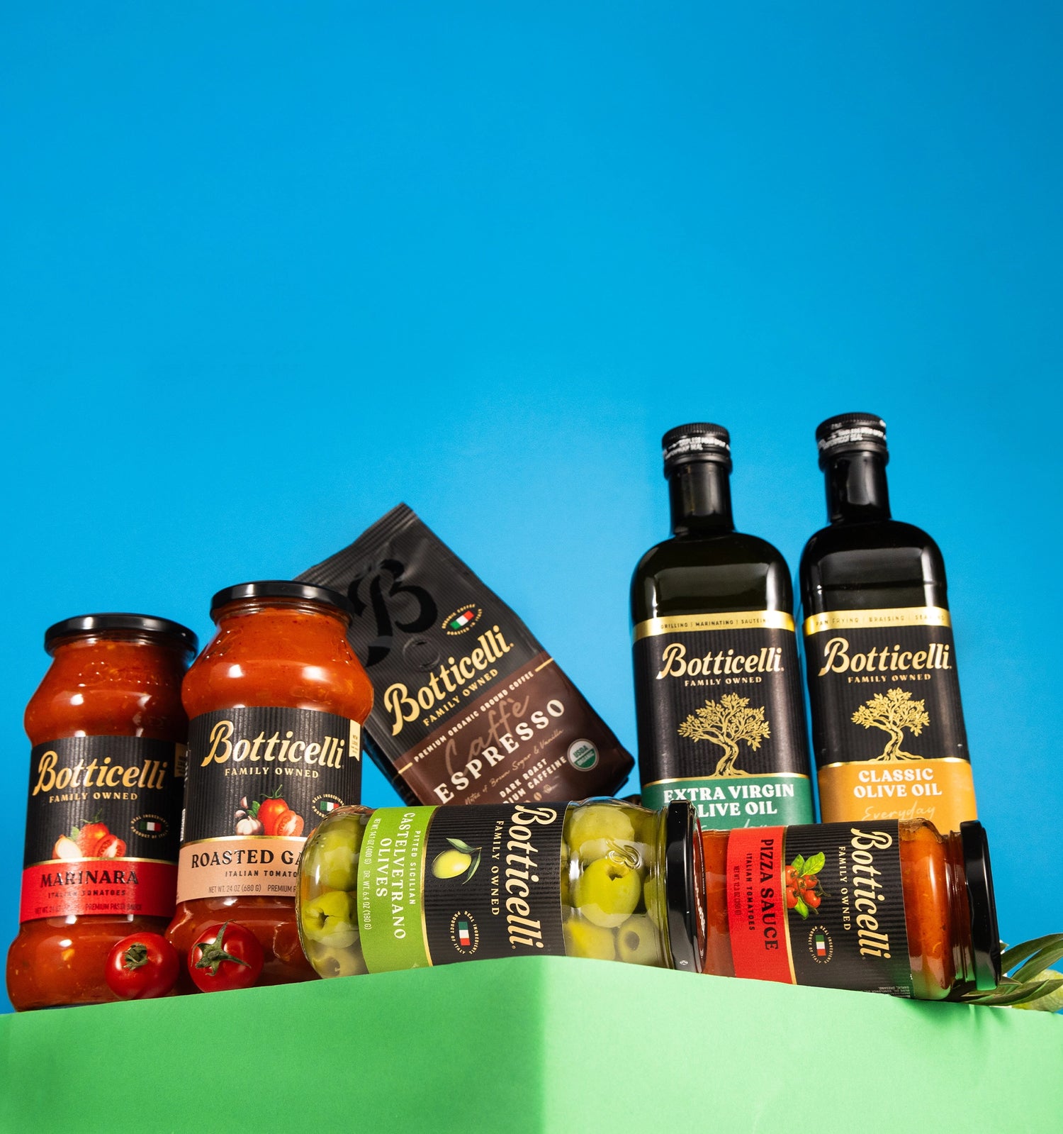 Botticelli food and beverage products including sauces and oils on a green surface with a blue background
