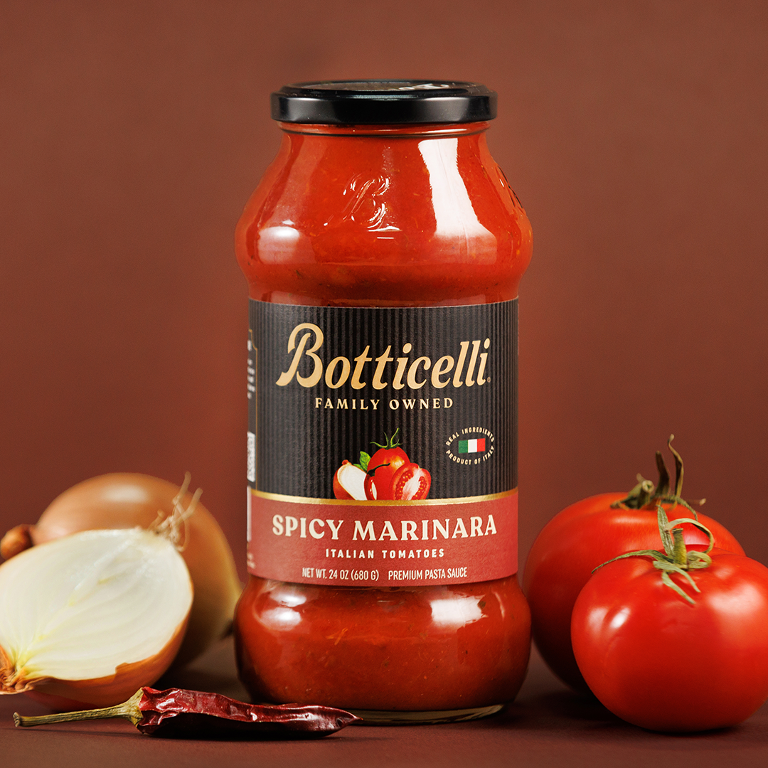 Botticelli Spicy Marinara sauce jar with tomatoes and onions on a brown background