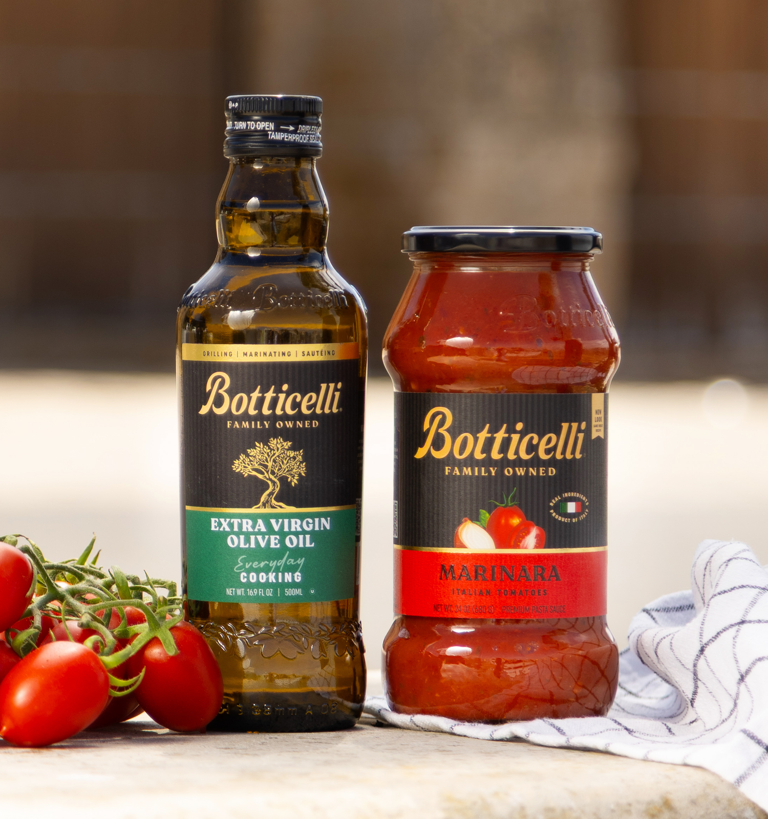 Botticelli cooking extra virgin olive oil and marinara sauce bottles on a table in Italy with tomatoes.