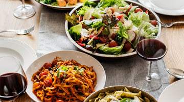 a dinner table set with Italian food for serving