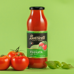 Bottle of Botticelli Passata with Basil on a green background with tomatoes and basil leaves.
