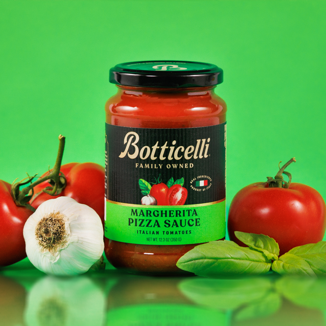 Botticelli Margherita Pizza Sauce jar with tomatoes, garlic, and basil on a green background