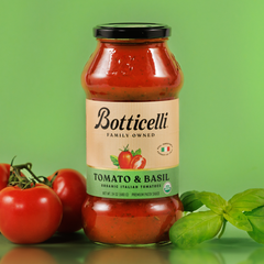 Botticelli tomato and basil pasta sauce jar with tomatoes and basil on a green background